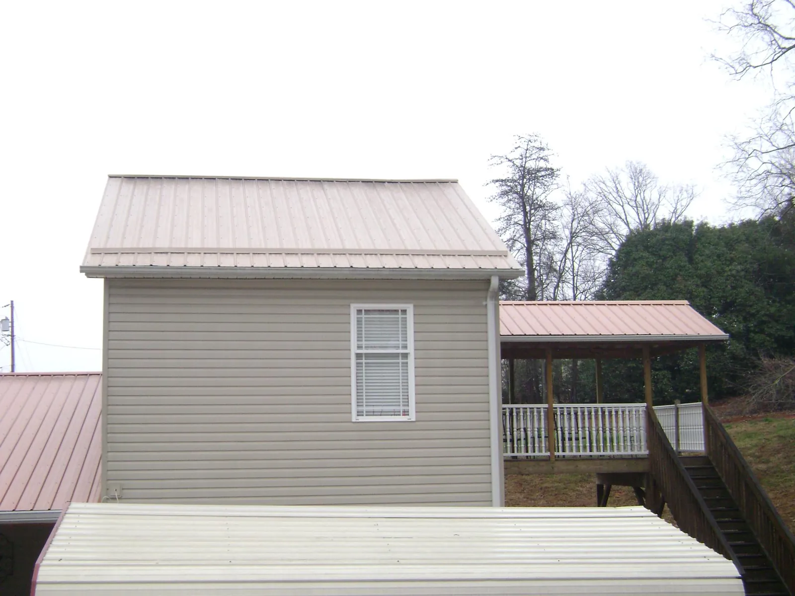 Tan metal roofs on a two story addition and attached porch, from a Roof Replacement job in Langley